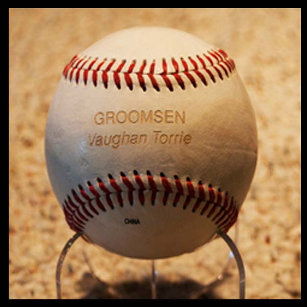 Baseball resting on a wire stand with the words 'Groomsman Vaughan Torrie' engraved on the surface.